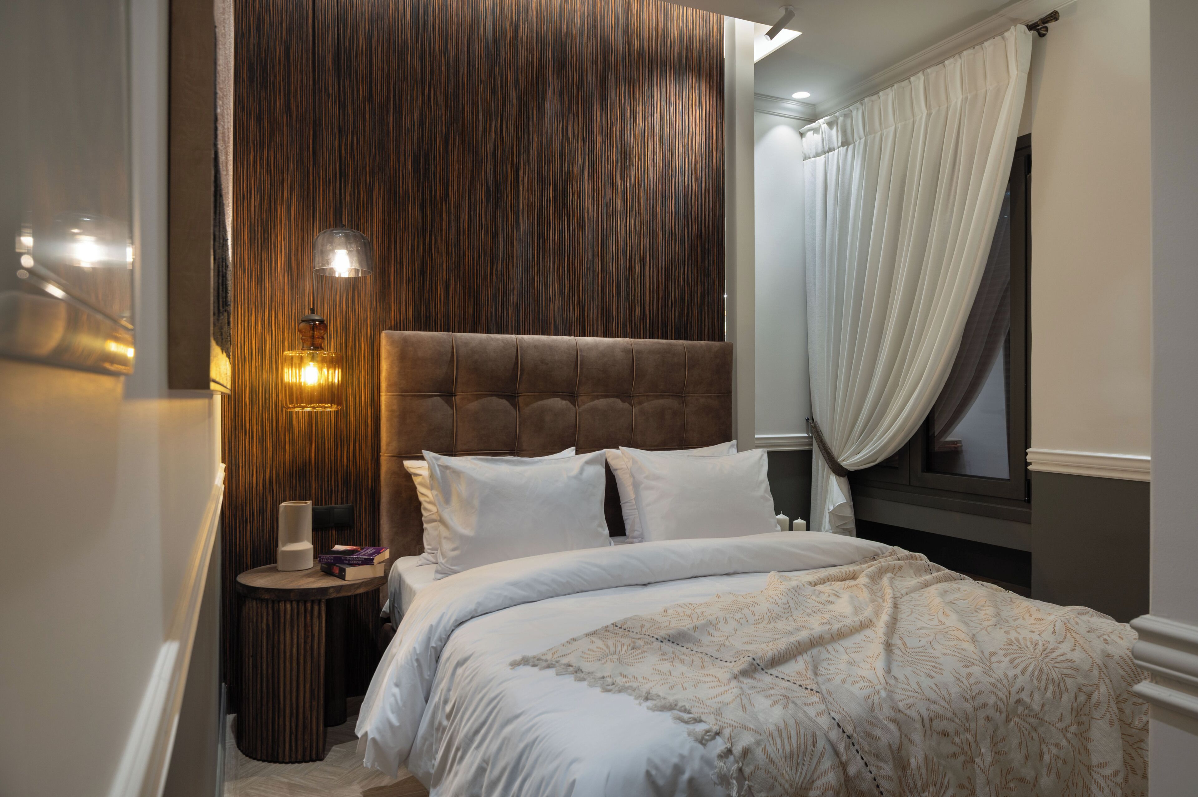 Un dormitorio con una cama grande, una pared de acento de madera y una mesita de noche con lámpara.