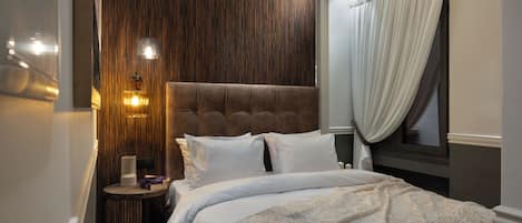 A bedroom with a large bed, a wooden accent wall, and a nightstand with a lamp.