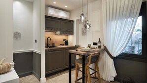 A modern kitchen with dark cabinets, a wooden countertop, and pendant lighting. - Kosmitis Suites Athens (Athens)