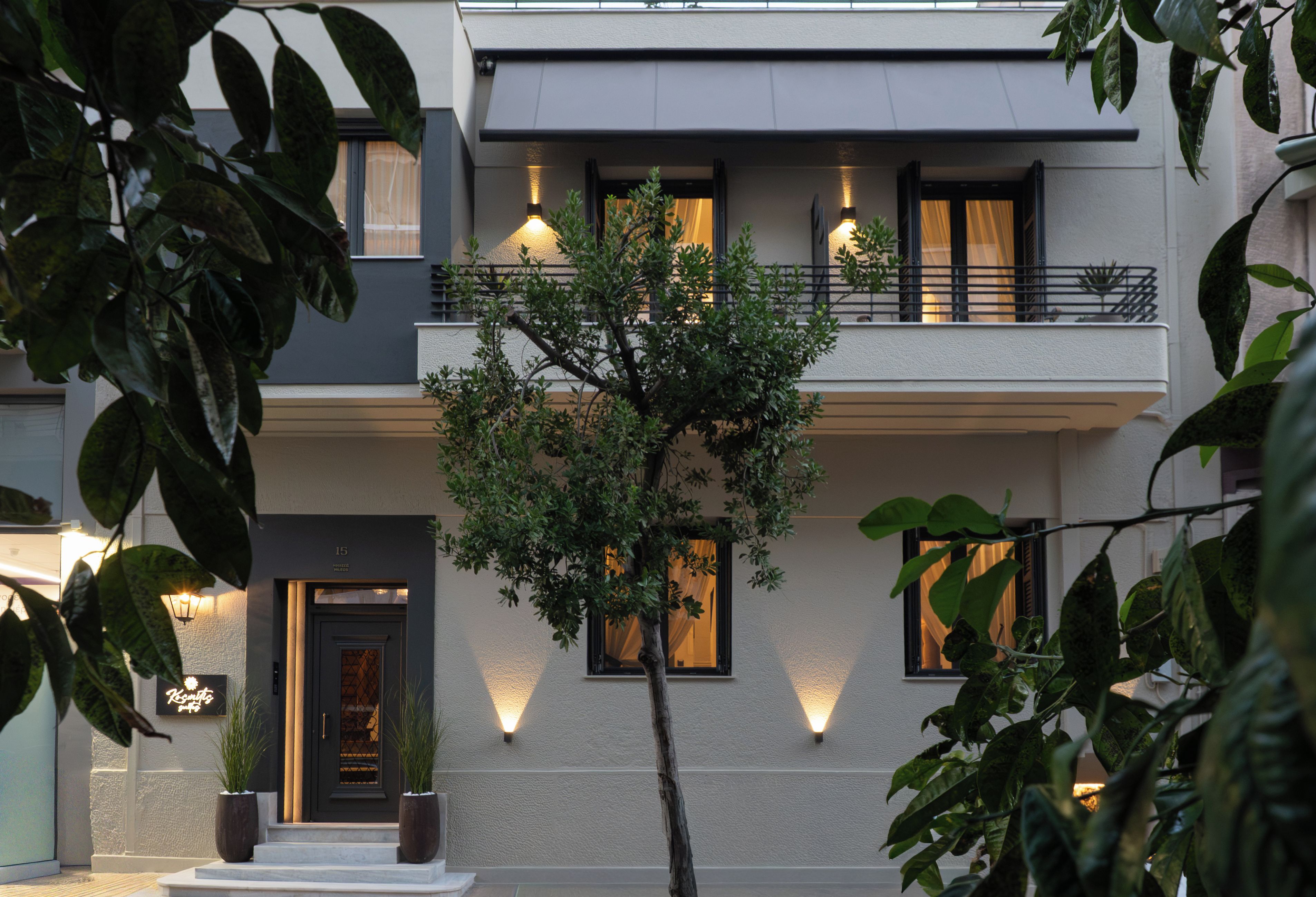 Un edificio moderno de dos pisos con un balcón y un árbol en primer plano.