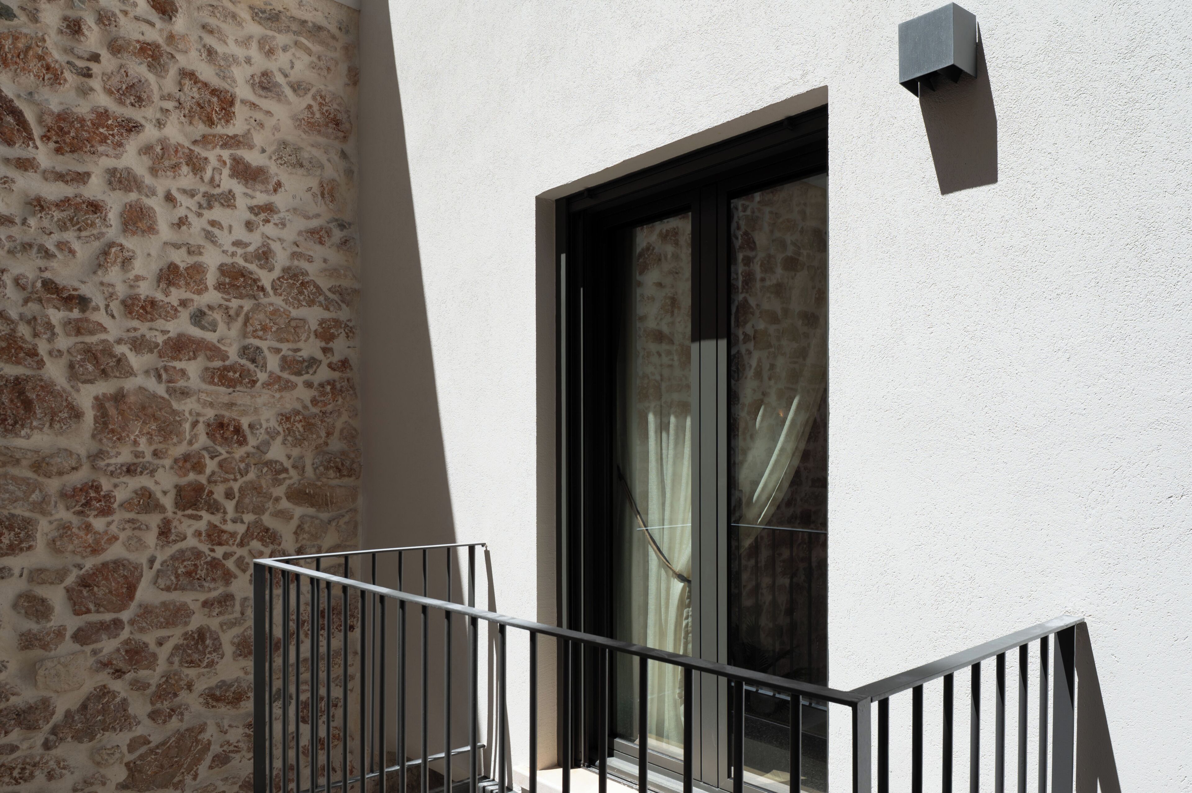 Un balcon avec un mur en pierre et une fenêtre avec des rideaux.