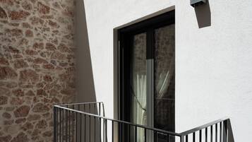 Un balcon avec un mur en pierre et une fenêtre avec des rideaux.