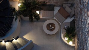 A circular seating area with a central table, surrounded by sofas and a staircase. - Kosmitis Suites Athens (Athens)