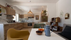 Een moderne keuken met houten kastjes, een marmeren aanrechtblad en een eethoek met een tafel gedekt voor twee personen.