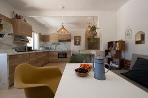 Eine moderne Küche mit Holzschränken, einer Marmorarbeitsplatte und einem Essbereich mit Tisch für zwei Personen.