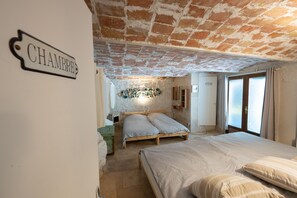 Ein Schlafzimmer mit Ziegeldecke, einem Bett mit weißer Bettwäsche, einem Holz-Kopfteil und einer wandmontierten Leuchte.