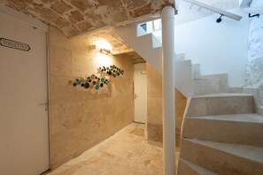 Eine Treppe mit Handlauf, eine Wand mit dem Schriftzug 'TOILETTES' und einem dekorativen Wandelement.