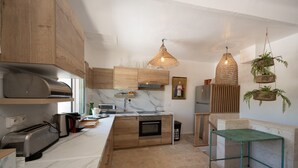 Een moderne keuken met houten kastjes, een ingebouwde oven, een marmeren aanrechtblad en hangende rieten lampen.