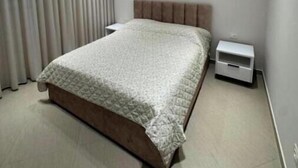 Um quarto moderno com uma cama, mesa de cabeceira e apoio para objetos pessoais.