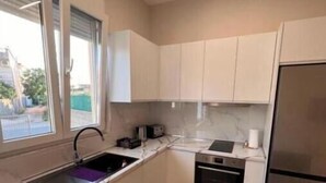 Uma cozinha compacta com forno embutido, geladeira e janela que proporciona luz natural.