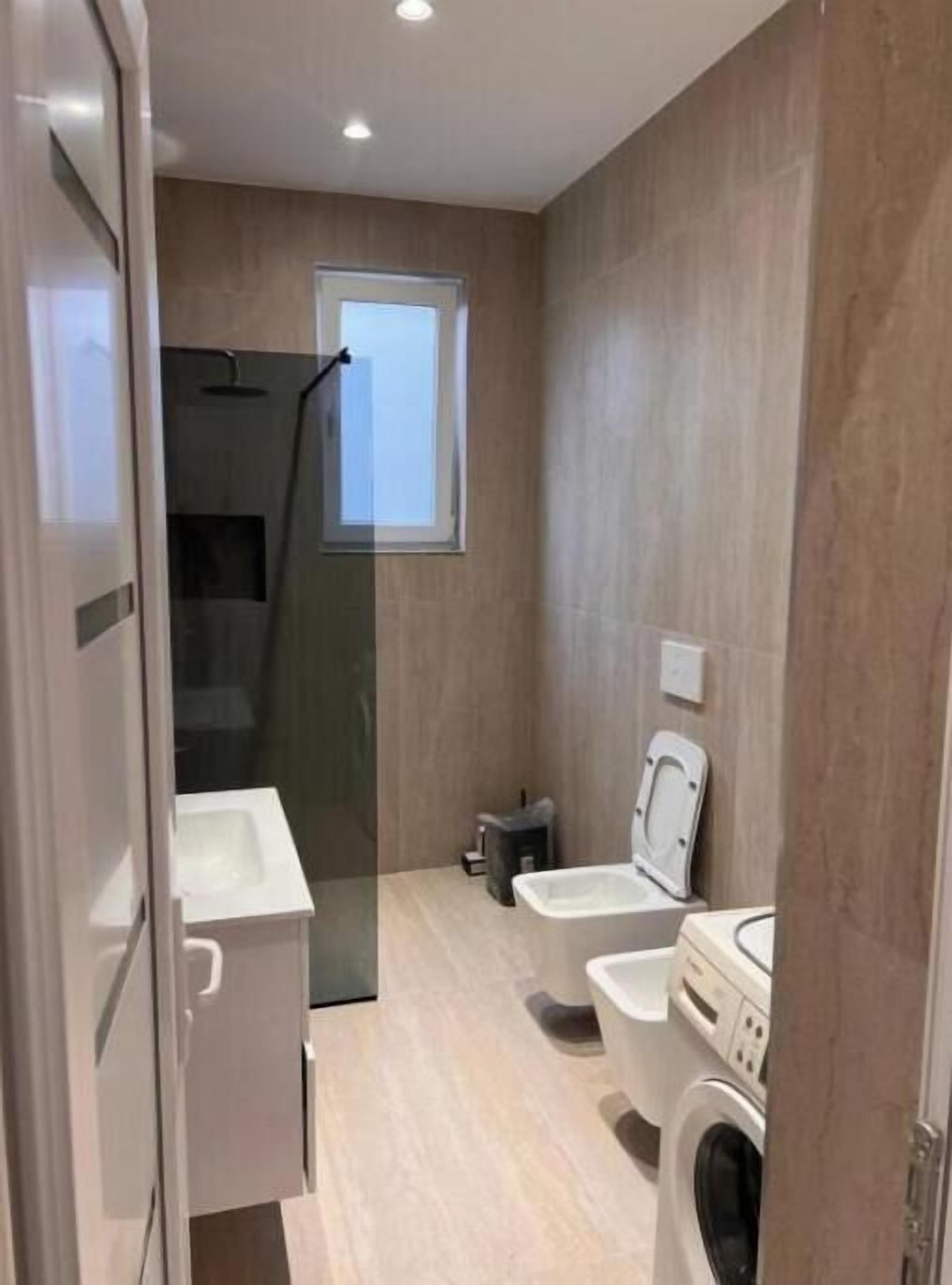 Une petite salle de bain comprenant une douche, des toilettes et un lave-linge.