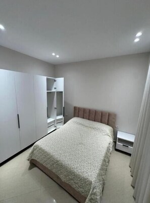 A bedroom with a bed, wardrobe, and bedside table.