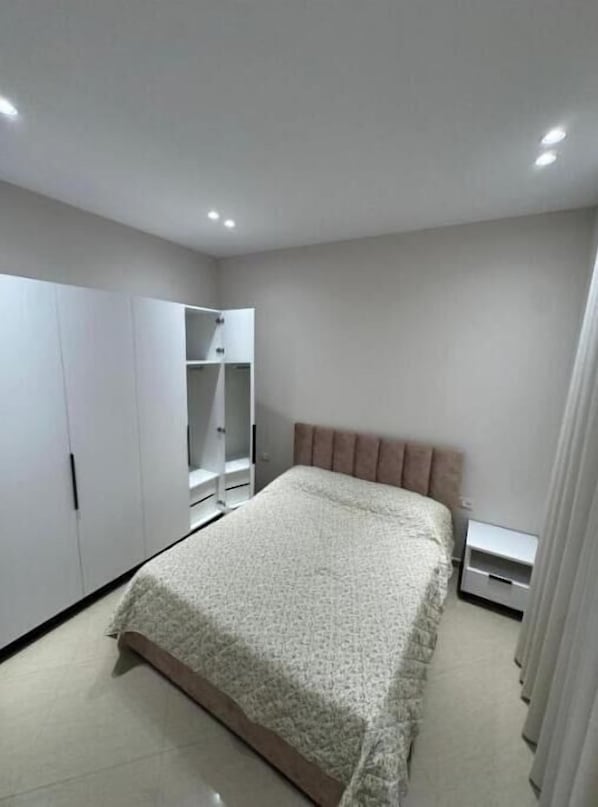 A bedroom with a bed, wardrobe, and bedside table.