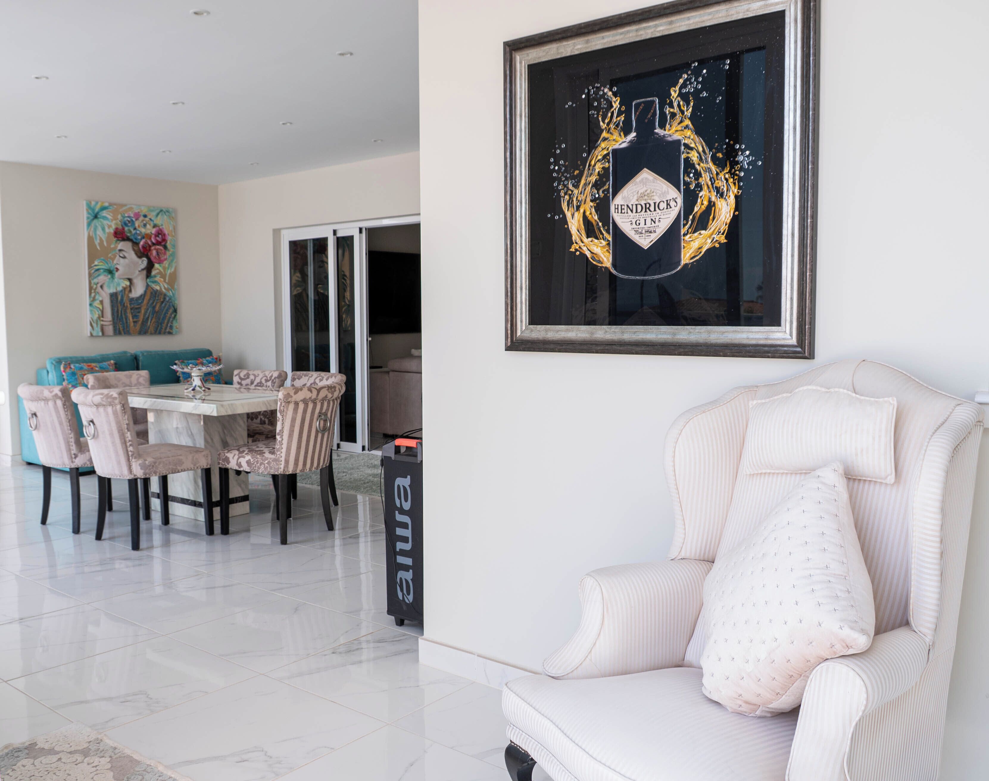 A modern dining area with a table and chairs, a sofa, and a framed artwork on the wall.