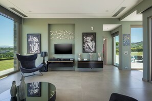 A modern living room with a flat-screen TV, artwork, and a view of the outdoors. - Villa Apollo (Agia Marina)
