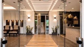 Un hall d’entrée moderne avec une cloison en verre, un plancher en bois et un escalier menant à un niveau supérieur.