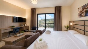 A hotel room with a bed, a desk, a TV, and a view of the outdoors.