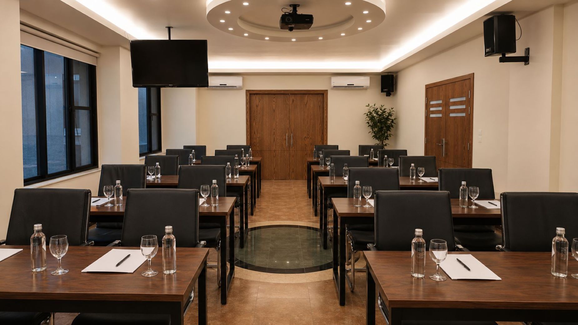 Uma sala de conferências com várias mesas, cadeiras, um projetor e uma tela grande.