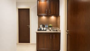A compact kitchen with wooden cabinets, a countertop, a sink, and a door.