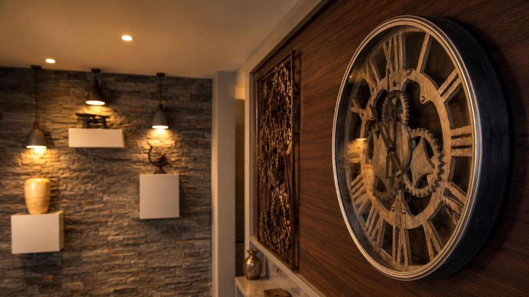Pared con un gran reloj de madera, pared de piedra y lámparas colgantes.