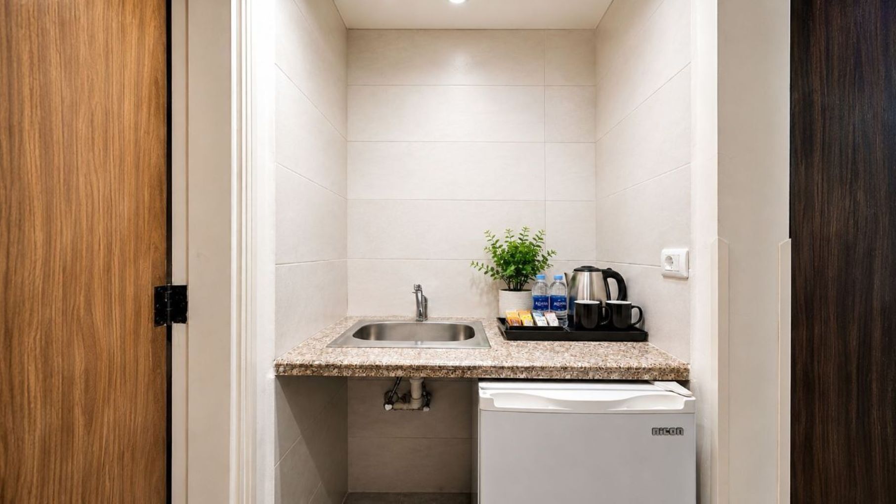 A compact kitchen with a sink, countertop, and a small refrigerator.