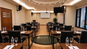 A conference room with multiple tables, chairs, a projector screen, and a large window. - Iris Flower (Jezzine)