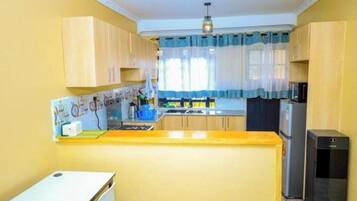 A compact kitchen with wooden cabinets, a central island, and a refrigerator.