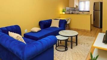 A compact living space with a sofa, a small dining table, and a kitchenette area.