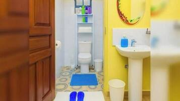 Un baño con un lavamanos blanco, un espejo y un tapete azul en el suelo.