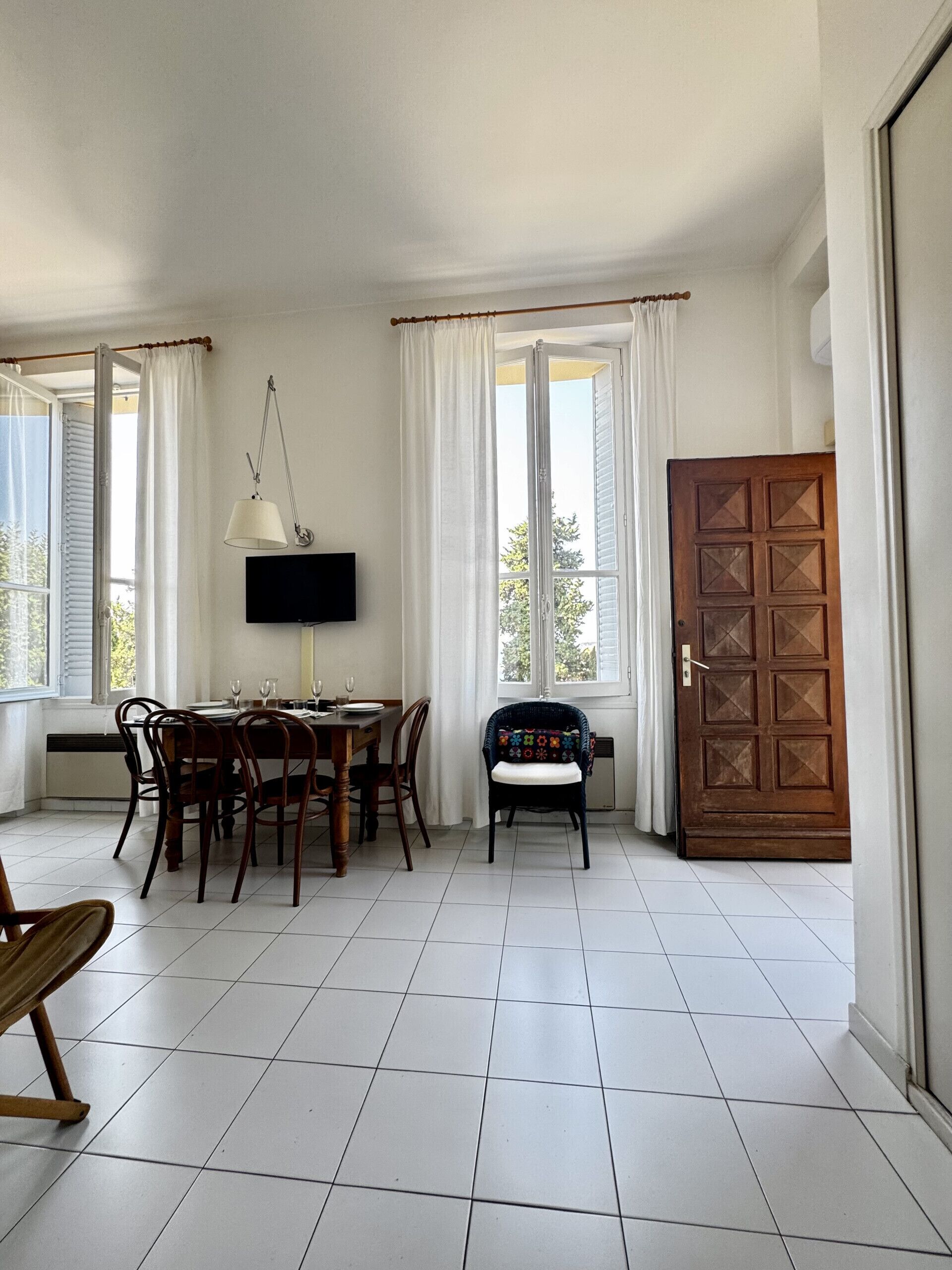Un espace repas comprenant une table, des chaises, un téléviseur et une porte.