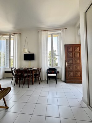 A dining area with a table, chairs, a television, and a door. - Cosy appartement à Menton Garavan (Menton)