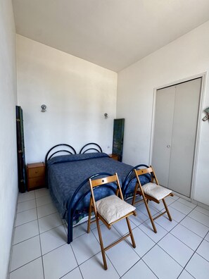 Ein Schlafzimmer mit einem Bett, zwei Holzstühlen, einem Nachttisch und einem Kleiderschrank.