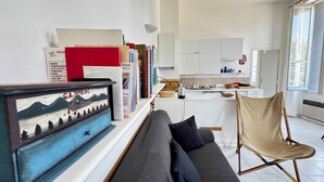 En moderne stue med en sofa, en lænestol og en bogreol med bøger og et indrammet billede.