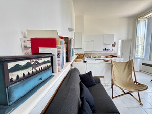 Ein modernes Wohnzimmer mit einer Couch, einem Sessel und einem Bücherregal mit Büchern und einem gerahmten Bild.