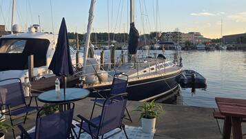 A marina with boats docked, outdoor seating with umbrellas, and a clear sky.