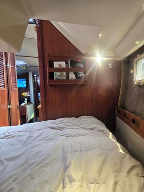 A bedroom with a bed, a wooden shelf with books, and a window. -  3-Bed Yacht in Muskegon w/ Sail Kayaks \& Beach Trail/AC/Heat/wireless internet (Muskegon)