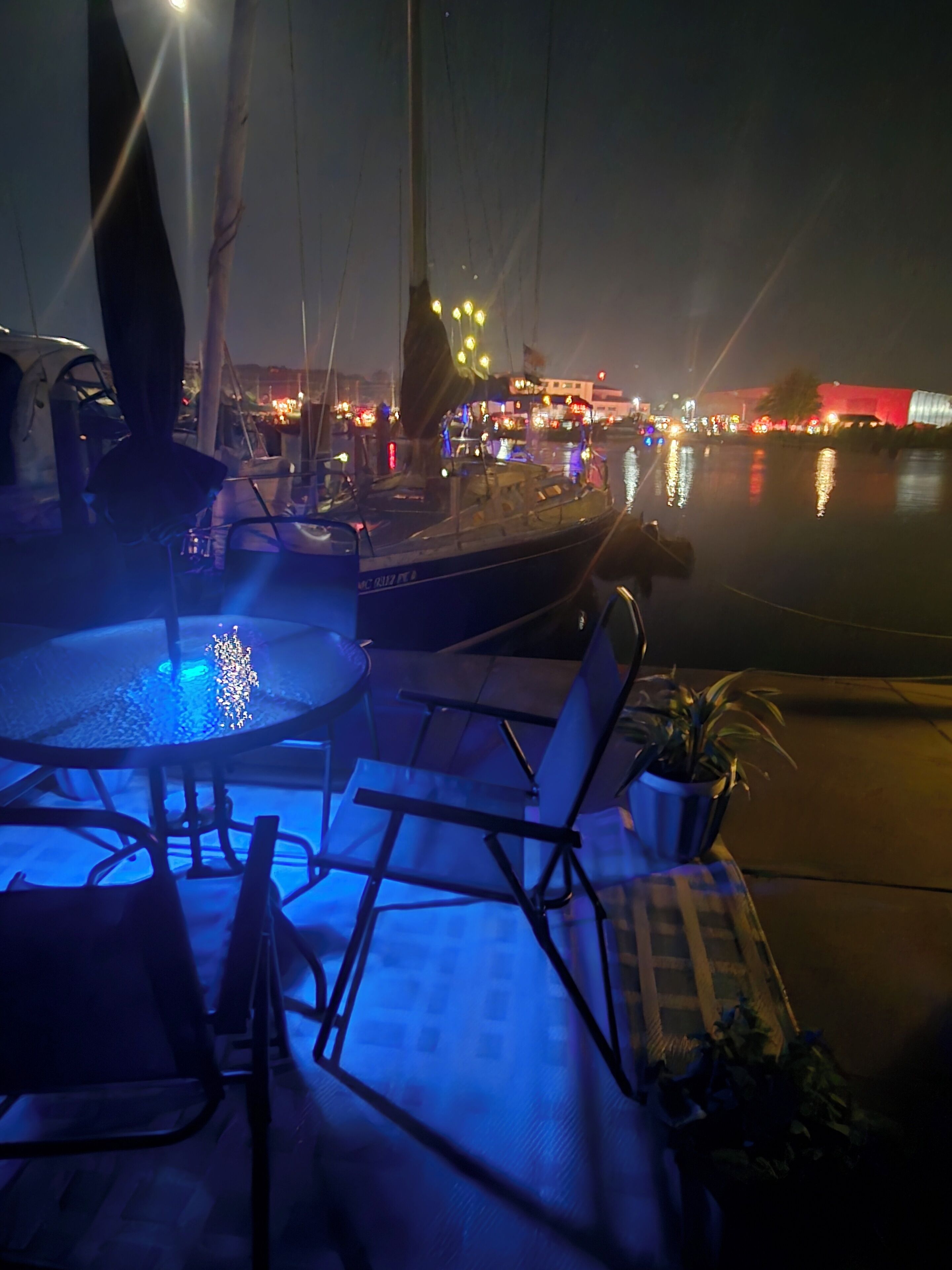 A nighttime marina with boats, a pool, and lounge chairs.