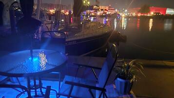 A nighttime marina with boats, a pool, and lounge chairs.