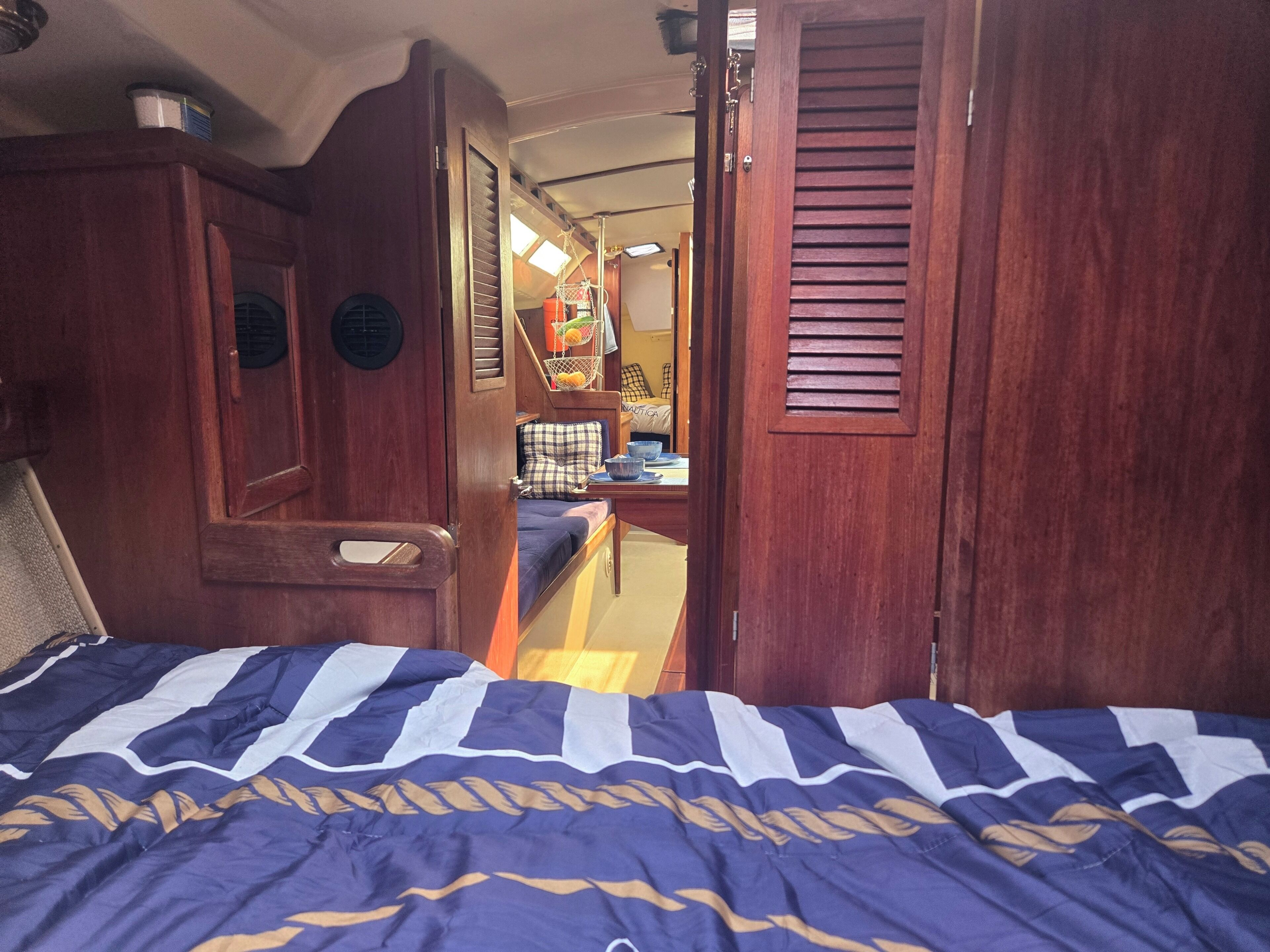 Een slaapkamer met een bed, een houten garderobe en een zithoekje met een kussen.