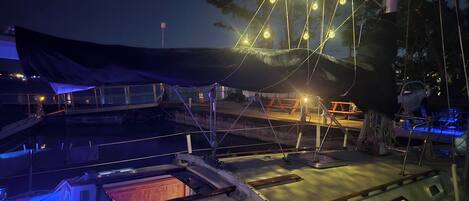 A boat deck with a covered area, a table, and a railing.