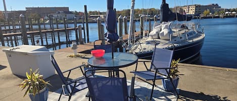 A marina with a docked sailboat, a table with chairs, and a potted plant.