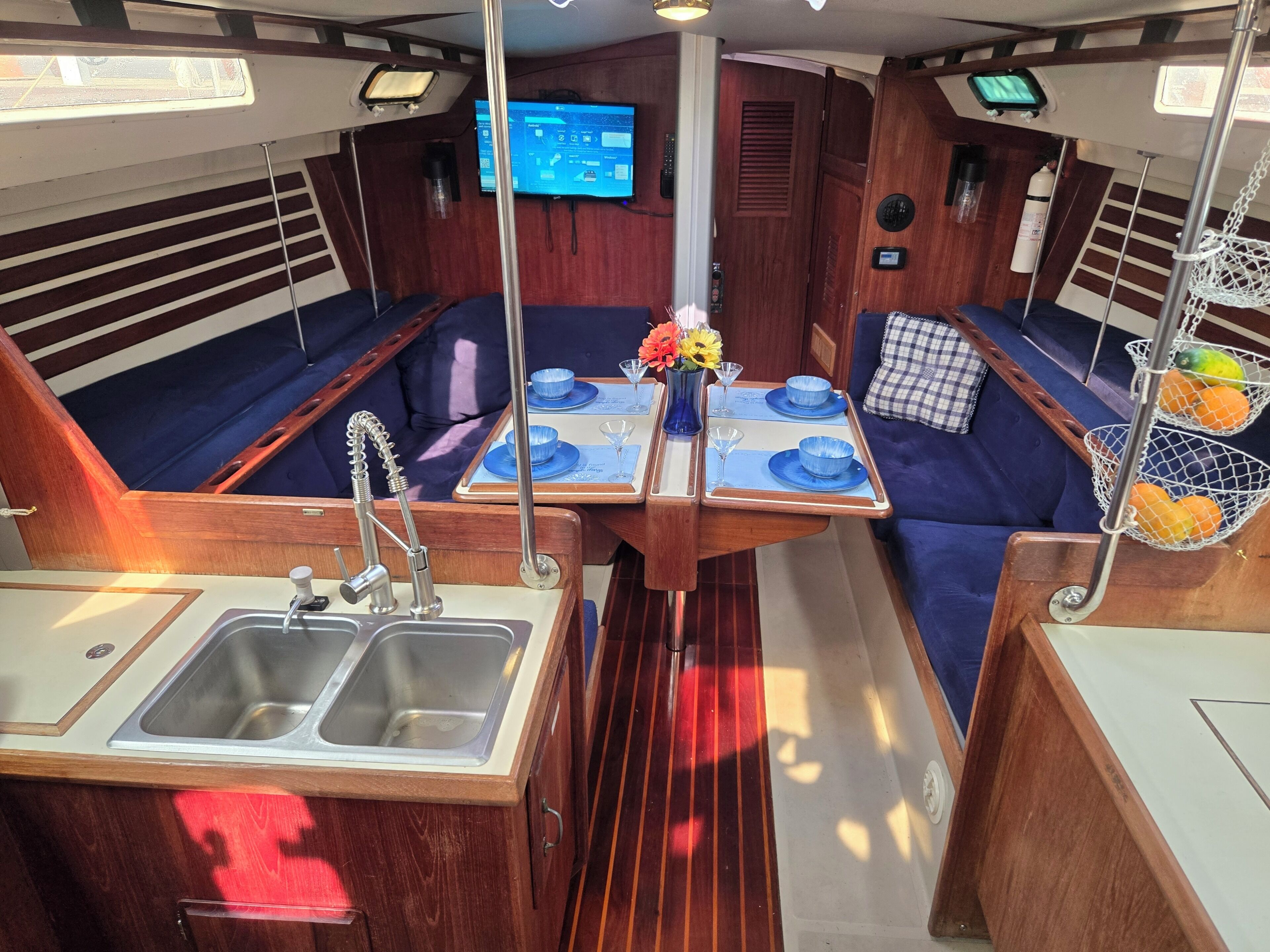 A boat's interior with a dining area, a sink, and a television.