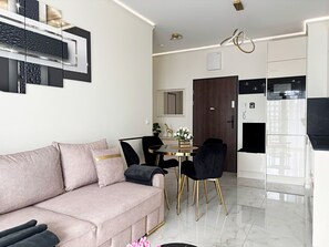 Un salon moderne comprenant un canapé, une table à manger et des chaises. Il y a également un coin cuisine avec un réfrigérateur et un four à micro-ondes.
