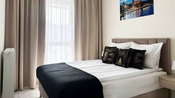 Ein Hotelzimmer mit einem Bett, Vorhängen, einem Nachttisch und einem an der Wand hängenden Bild.