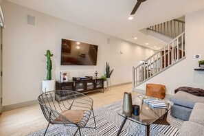 Ein modernes Wohnzimmer mit Flachbildfernseher, einer Treppe und einem Essbereich mit Glastisch.