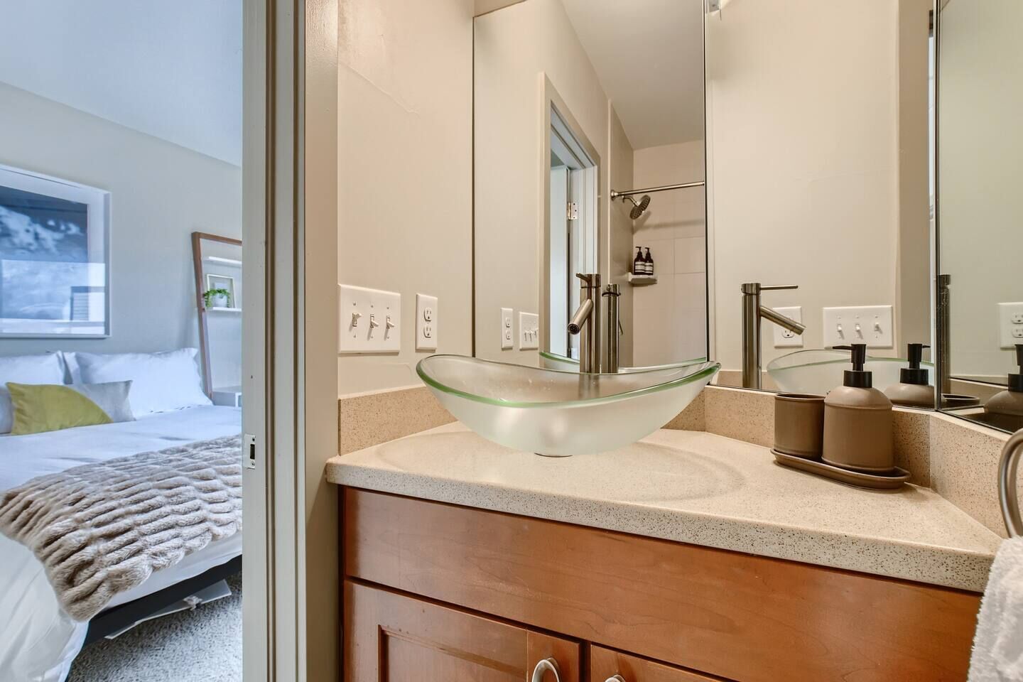 A modern bathroom with a glass vessel sink, a large mirror, and a shower.