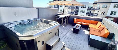Une terrasse sur le toit avec un jacuzzi, des sièges d’extérieur et une table.