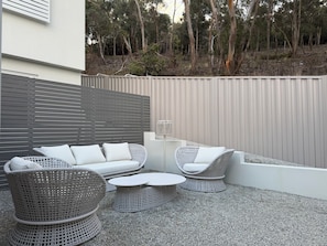 Ein Patio mit Korbmöbeln, einem runden Tisch und einer Lampe.