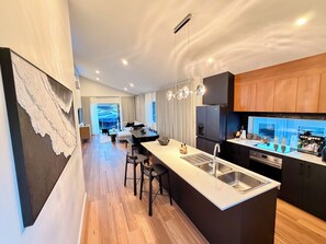 A modern kitchen with a central island, bar stools, and a built-in oven. - Luxury Lenah Valley Retreat, Minutes to MONA & CBD (Lenah Valley)