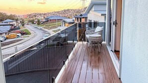 Ein Balkon mit Blick auf ein Wohngebiet, einer Holzterrasse und einem Glasgeländer.